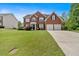 Beautiful red brick home with mature landscaping, a green lawn, and an attached two-car garage at 3477 Seneca Farm Dr, Buford, GA 30519