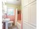 Retro pink tiled bathroom with a pedestal sink, toilet, and a shower/tub combination with built-in storage at 2227 Leafmore Drive, Decatur, GA 30033