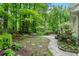 Serene backyard featuring a stone path, lush landscaping, and a wooded backdrop with a sitting area at 4152 Barberry Ne Dr, Roswell, GA 30075