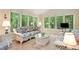 Bright living room with picture windows overlooking lush greenery, floral patterned wicker furniture, and tile flooring at 4152 Barberry Ne Dr, Roswell, GA 30075