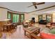 Open living room with hardwood floors, natural light, fireplace, a ceiling fan, and views of the wooded backyard at 4152 Barberry Ne Dr, Roswell, GA 30075