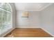 Bright, empty room with hardwood floors, neutral walls, and a large window for ample natural light at 1035 Eagles Brooke Dr, Locust Grove, GA 30248