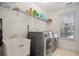 Functional laundry room with modern washer and dryer units, storage shelving, and natural light at 1035 Eagles Brooke Dr, Locust Grove, GA 30248