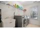 Functional laundry room featuring modern washer and dryer, storage shelves, and utility sink at 1035 Eagles Brooke Dr, Locust Grove, GA 30248