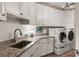 Well-lit laundry room includes stainless sink, granite countertops, and modern front load washer and dryer at 50 Canton St # 406, Alpharetta, GA 30009