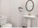 Elegant half bathroom featuring a pedestal sink, oval mirror, and classic fixtures at 112 Leveret Rd, Locust Grove, GA 30248