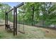 Wood swing set in a backyard with mature trees and partial view of a lake with a fence at 2548 Lakeview East Se Trl, Atlanta, GA 30316