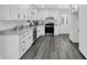 Well-lit kitchen featuring white cabinets, stainless steel appliances, granite countertops, and wood-look flooring at 5774 Forest Dr, Acworth, GA 30102