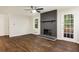Spacious living room featuring a painted brick fireplace, hardwood floors, and a ceiling fan at 1019 Crestwood Ln, Stone Mountain, GA 30087