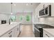Bright kitchen featuring white cabinets, island with a sink, stainless appliances, and tile backsplash at 1651 Tide Mill Rd, Cumming, GA 30040