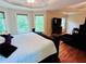 Main bedroom with tray ceiling, hardwood floors, a tv, and lots of natural light at 1345 Starboard Way, Cumming, GA 30041