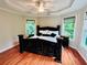 Main bedroom featuring a large bed, tray ceiling, hardwood floors, and ample windows at 1345 Starboard Way, Cumming, GA 30041