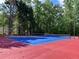 A blue and red tennis court, surrounded by tall trees, offers a private and scenic setting for sports at 1345 Starboard Way, Cumming, GA 30041