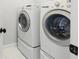 Bright laundry room with modern washer and dryer units on pedestals at 217 Napa Dr, Woodstock, GA 30188