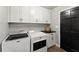 Well-organized laundry room with white cabinets, black hardware and countertops, with a front-loading washer and dryer set at 4433 Windsor Oaks Cir, Marietta, GA 30066