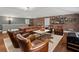 Spacious living room with exposed brick, leather furniture, and hardwood floors offers a cozy and inviting atmosphere at 6805 Bucks Rd, Cumming, GA 30040