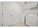 Bright laundry room equipped with a washer, dryer, wire shelving, and a tiled floor at 100 Grove View Rd, Woodstock, GA 30189