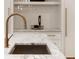 Close-up of a kitchen sink featuring marble countertops, sleek gold faucet, and modern design at 490 Mount Paran Rd, Atlanta, GA 30327