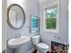 Charming powder room with pedestal sink, round mirror, and stylish accents at 4625 Cold Spring Court, Cumming, GA 30041