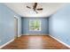 Bright bedroom featuring blue walls, wood-look flooring, a ceiling fan and a large window at 2465 Brianna Dr, Hampton, GA 30228