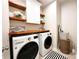 Bright laundry room equipped with modern washer and dryer, and custom shelving for storage at 688 Saffron Blvd, Lawrenceville, GA 30045