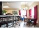 An open-concept living and dining area with hardwood floors, bright red curtains, and views to the kitchen at 7270 Williamsburg Dr, Riverdale, GA 30274