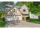 Two-story home with a two-car garage, a green lawn, and mature trees at 5010 Foxberry Ln, Roswell, GA 30075