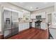 Modern kitchen with stainless steel appliances and white cabinetry, complemented by rich hardwood floors at 5010 Foxberry Ln, Roswell, GA 30075