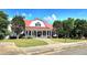 Charming two-story farmhouse with red metal roof, white siding, covered porch, and meticulously landscaped front yard at 205 Kestrel Cir, Covington, GA 30014