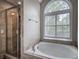 Bright bathroom featuring a soaking tub and a shower with glass door next to an arched window at 3186 Sail Winds Nw Dr, Acworth, GA 30101