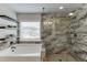 This luxurious bathroom features neutral-toned tile in the shower, floating shelves over the tub, and natural light at 3939 Soft Wind Ter, Buford, GA 30518