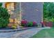 A stone pathway leads alongside a home, revealing meticulously manicured landscaping, flowers, and lighting at 3939 Soft Wind Ter, Buford, GA 30518