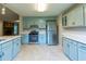 Bright kitchen featuring blue cabinets, stainless steel appliances, and tile flooring at 1451 Brays Mill Trce, Lawrenceville, GA 30044