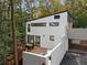 Exterior of a modern home featuring a deck with outdoor seating, and bridge to the carport, nestled in a wooded area at 1153 Dawn View Nw Ln, Atlanta, GA 30327