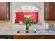 A double sink is inset in a kitchen counter with plants in front of a red accent wall at 2212 Nichols Valley Drive, Dacula, GA 30019