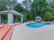 Beautiful backyard featuring a sparkling pool, pool house, and covered outdoor seating area, ideal for entertaining at 302 Gilmer Ct, Canton, GA 30115