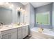 Bright bathroom with double vanity, modern fixtures, soaking tub, and large window at 2140 Ravencliff Dr, Austell, GA 30168