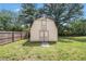 A backyard shed with double doors sits in the backyard against the backdrop of a wooden fence and lush trees at 578 Laney Rd, Locust Grove, GA 30248
