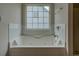 Bright bathroom featuring a tiled jacuzzi tub beneath a window at 4952 Terrace Dr, Ellenwood, GA 30294