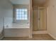 Bright bathroom featuring a tiled jacuzzi tub beneath a window, and a glass door shower at 4952 Terrace Dr, Ellenwood, GA 30294