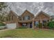 Charming two-story brick home with landscaped front yard, dark shutters and a two car garage on an overcast day at 4952 Terrace Dr, Ellenwood, GA 30294