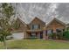 Charming two-story brick home with landscaped front yard, dark shutters and a two car garage on an overcast day at 4952 Terrace Dr, Ellenwood, GA 30294