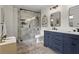 Bright bathroom featuring a glass enclosed shower with white marble surround, navy blue vanity, and neutral-toned rug at 94 Glenn Se St, Atlanta, GA 30312