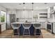 Bright kitchen features stainless steel appliances, white cabinetry, quartz countertops, and a navy blue kitchen island at 94 Glenn Se St, Atlanta, GA 30312