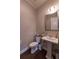 Cozy powder room with pedestal sink, decorative mirror, and stylish neutral wall color at 10143 Windalier Way, Roswell, GA 30076