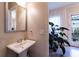 Bright powder room with pedestal sink, large plant, and access to the outdoor patio at 10143 Windalier Way, Roswell, GA 30076
