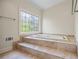 Bright bathroom featuring a tub with decorative tile, creating a spa-like oasis at 1402 Bromley Dr, Snellville, GA 30078