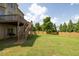 Expansive backyard featuring a wooden deck with stairs, lush greenery, and a privacy fence at 1584 Heartland Path, Hoschton, GA 30548