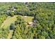 Aerial view of the home's treed lot with a meadow and barn, surrounded by other homes at 6980 Lamplighter Ln, Winston, GA 30187
