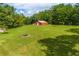 View of the large grassy backyard and red barn on the property surrounded by lush trees at 6980 Lamplighter Ln, Winston, GA 30187